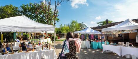Un mercado al aire libre con carpas blancas y mesas que exhiben diversos artículos.