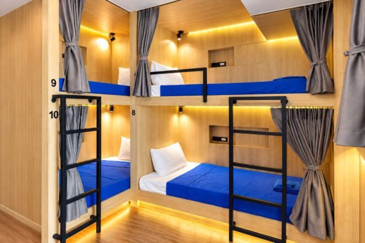 A bunk bed room with wooden walls, curtains, and a blue bedspread.
