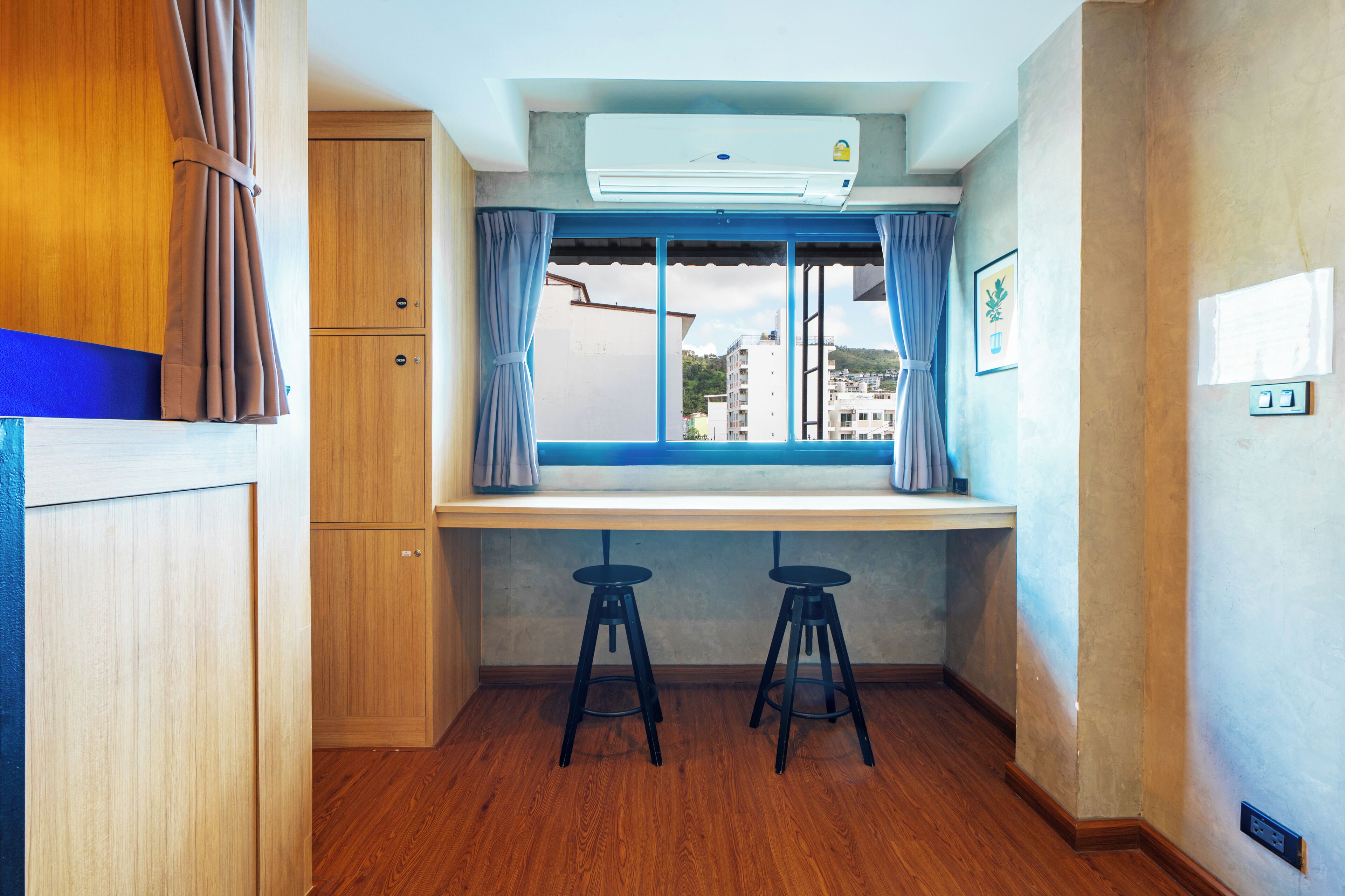 A compact kitchen with a window, two stools, and wooden cabinets.