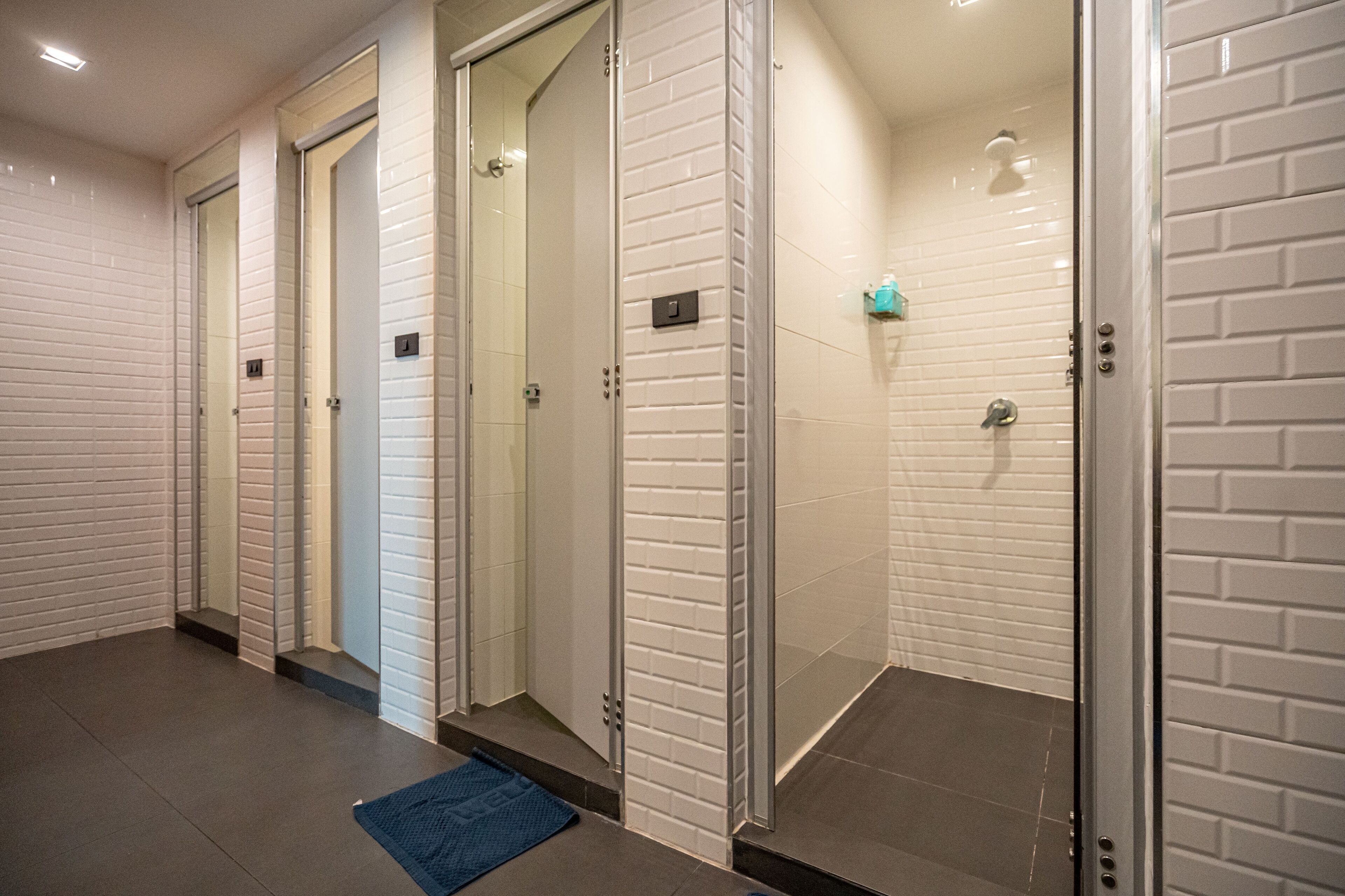 Ein Badezimmer mit weißen Ziegelwänden, einer Duschkabine aus Glas und einer blauen Matte auf dem Boden.