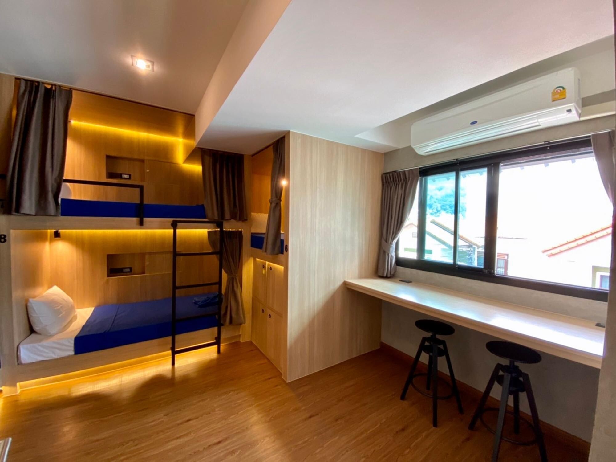 A compact room with bunk beds, a desk, and a window with curtains.