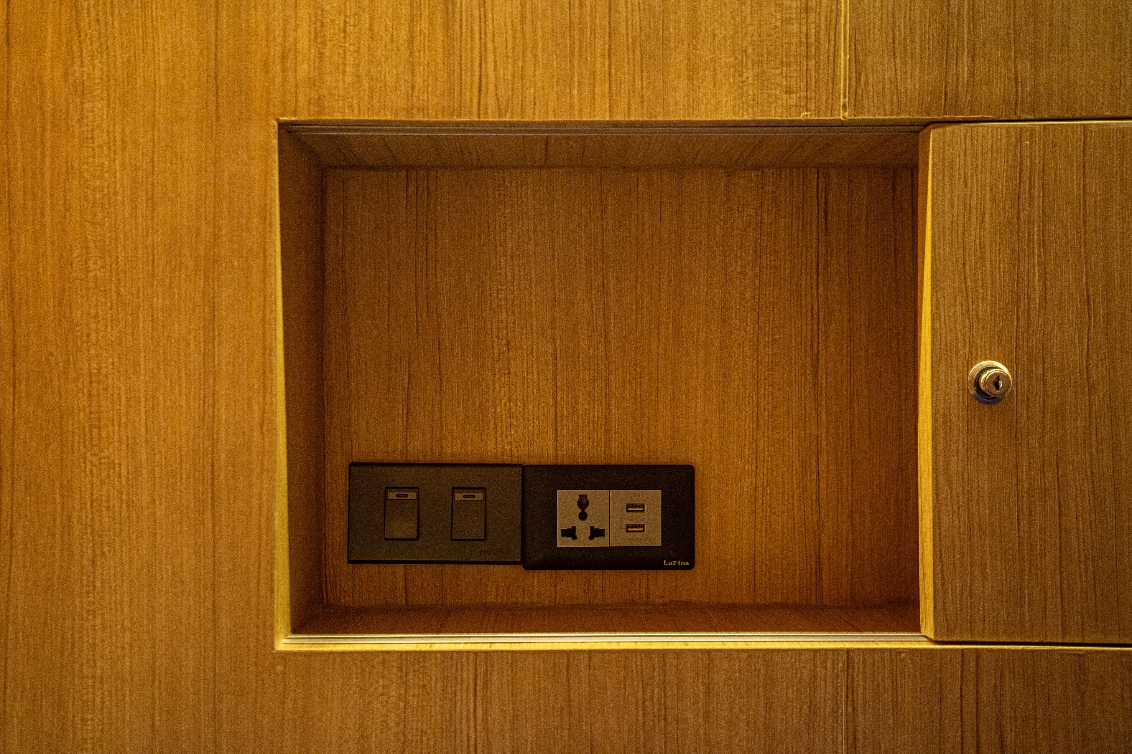 Un panel de madera con un enchufe eléctrico y un panel de interruptores.