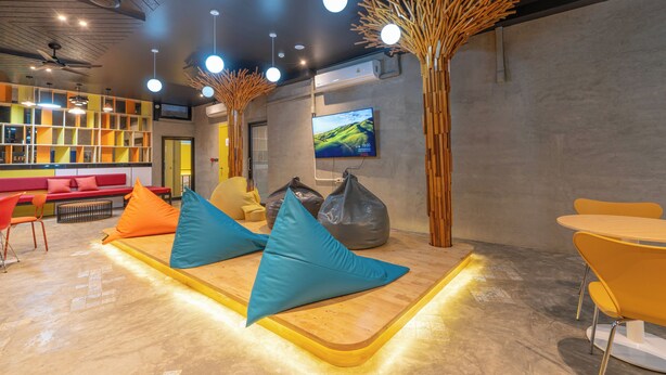 Ein stilvoller Lounge-Bereich mit Sitzgelegenheiten, einem Fernseher und einem Holzelement.