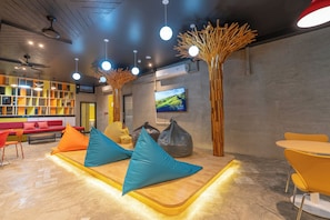 A modern lounge area with seating, a TV, and a wooden decor element. - Patong Poshtel - Adults Only - Hostel (Patong)