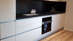 Une cuisine moderne avec des meubles blancs, un plan de travail noir et un four encastré.