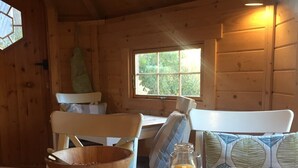 A wooden cabin interior with a dining table set for breakfast, including bowls, cups, a pitcher, and a bottle of orange juice. - Pandy B&B (Hereford)