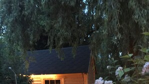 A wooden cabin with a window and a door, surrounded by greenery and a stone pathway. - Pandy B&B (Hereford)