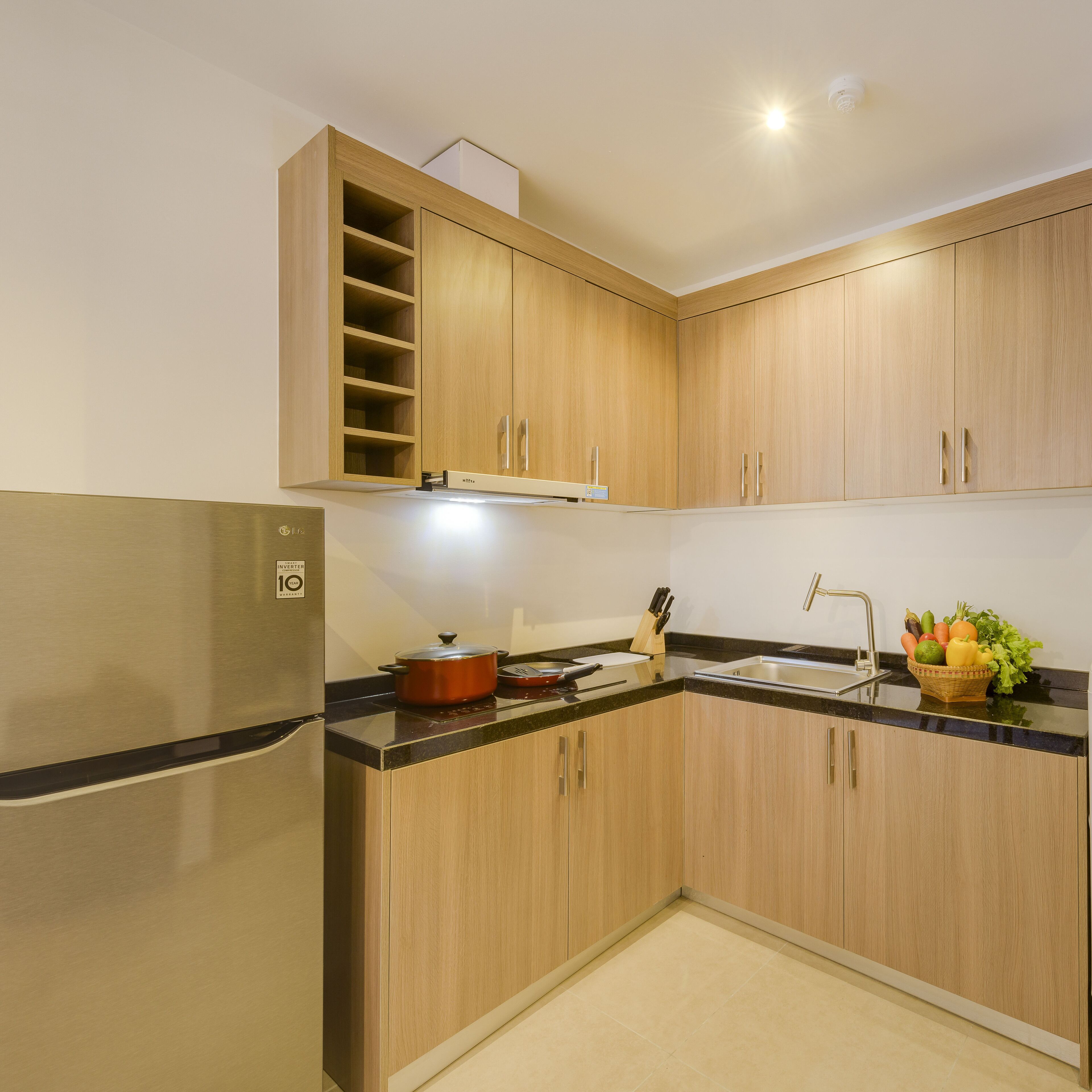 A modern kitchen with wooden cabinets, a stainless steel refrigerator, and a sink.