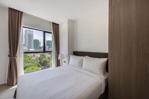 Quarto de hotel com uma cama grande, vista para a cidade e uma janela com cortinas.
