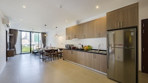 A modern kitchen with wooden cabinets, a stainless steel refrigerator, and a dining area with a table and chairs.