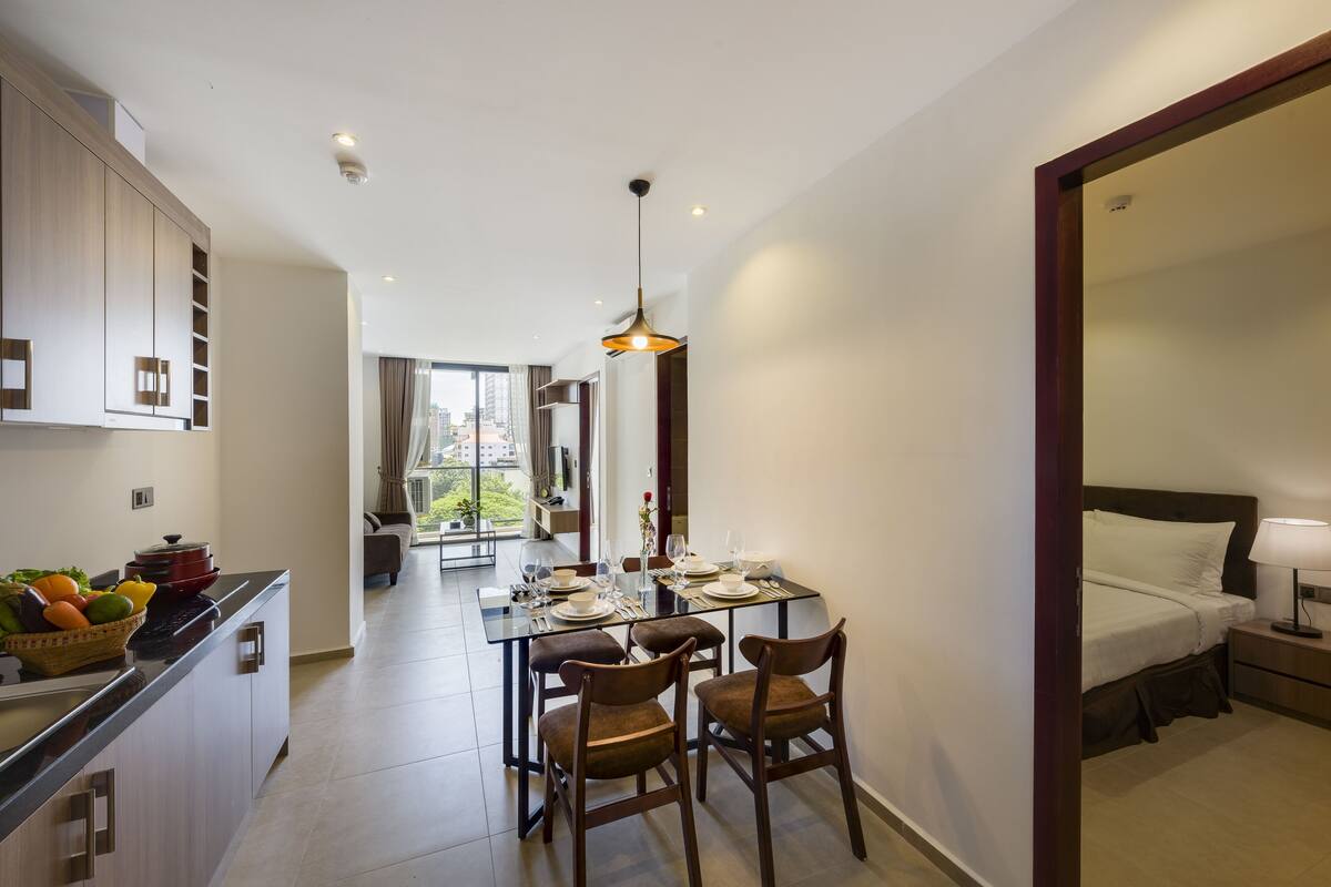 Une chambre d’hôtel moderne dotée d’un coin repas, d’une kitchenette et d’un grand lit.