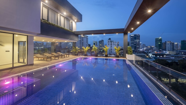 A rooftop infinity pool with city views, modern architecture, and lounge seating.
