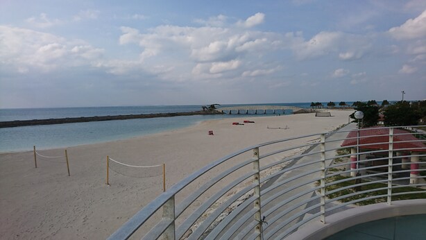 A beach with a metal railing, a volleyball net, and a lifeguard tower. - Free parking, free pets, free cleaning (糸満市)