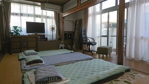A room with two beds, a desk with a television, a chair, and a large window. - Free parking, free pets, free cleaning (糸満市)