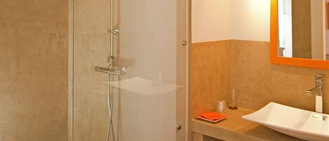 A modern bathroom with a glass-enclosed shower, a sink, and a mirror.