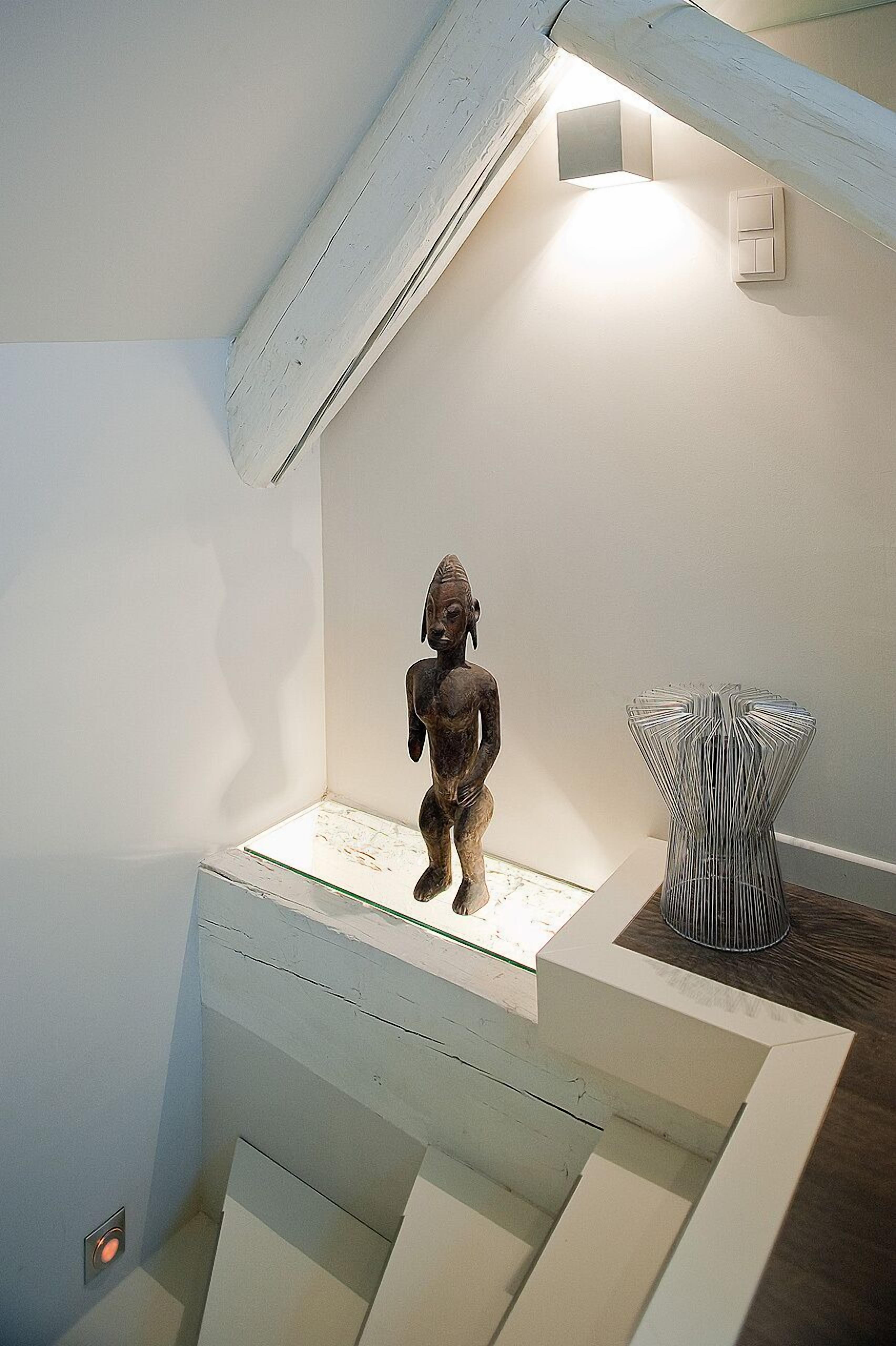 A staircase with a small statue and a metal sculpture on the landing.