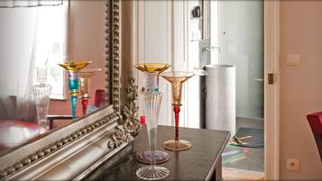 A room with a mirror reflecting a table with decorative glassware, a red chair, and a door with a glass panel.