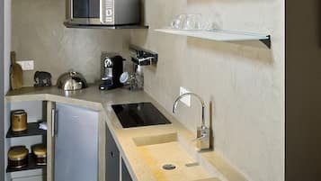 Una cucina moderna con forno a microonde integrato, macchina da caffè e un frigorifero compatto.