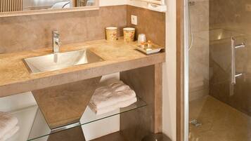 Une salle de bain moderne avec une douche à parois de verre, un meuble-lavabo à deux vasques et une étagère en verre située sous le lavabo.