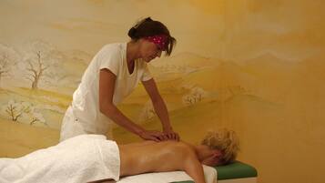 A massage therapy session in a room with a mural of a landscape.