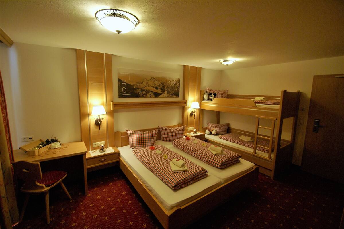 Een hotelkamer met een stapelbed, een bureau, een stoel en een spiegel.