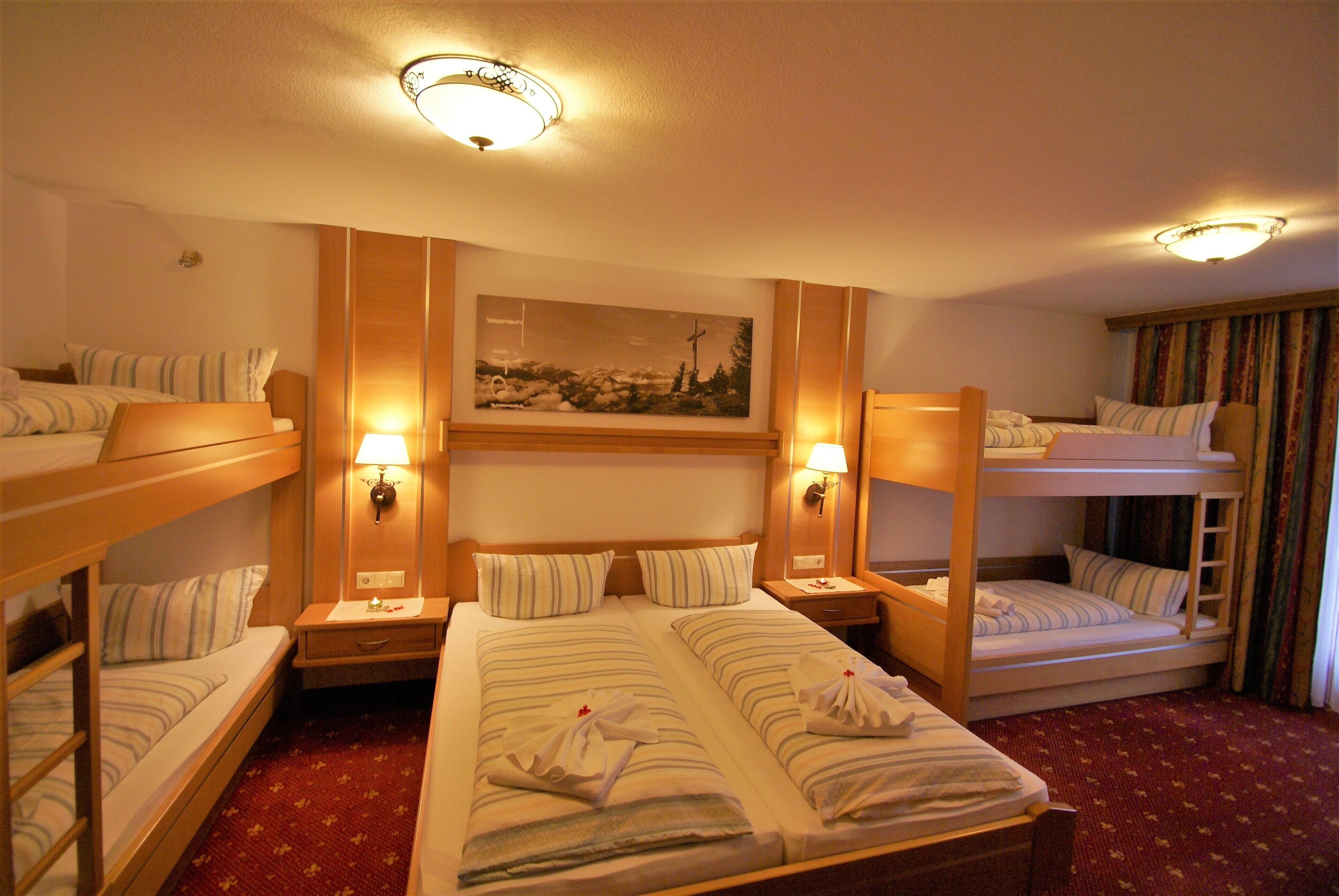 Una habitación de hotel con literas, una cama grande y un cuadro en la pared.