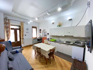 Ein kompakter Wohnbereich mit Essplatz, Küchenzeile und kleinem Fernseher.