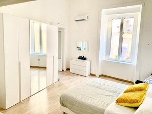 A bedroom with a bed, a wardrobe, a dresser, and a window.