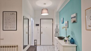 A hallway with a white door, a radiator, a bench, and a wall with framed artwork and a blue accent wall.