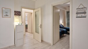 A modern interior with a hallway leading to a bedroom with a bed and a nightstand. There is a sign on the wall that says "Free Wi-Fi here."