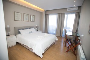 A hotel room with a large bed, bedside tables, a desk, and a chair. There are curtains on the windows and framed certificates on the wall. - Central Athens Loft (Athens)