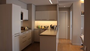Uma cozinha moderna com armários brancos, uma ilha central e forno embutido.