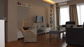 Uma sala de estar moderna com sofá, poltrona, televisão e estantes.