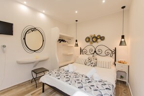 A neatly arranged bedroom with a bed, bedside table, and a mirror on the wall. - Naxos Enjoy Apartments (Naxos)