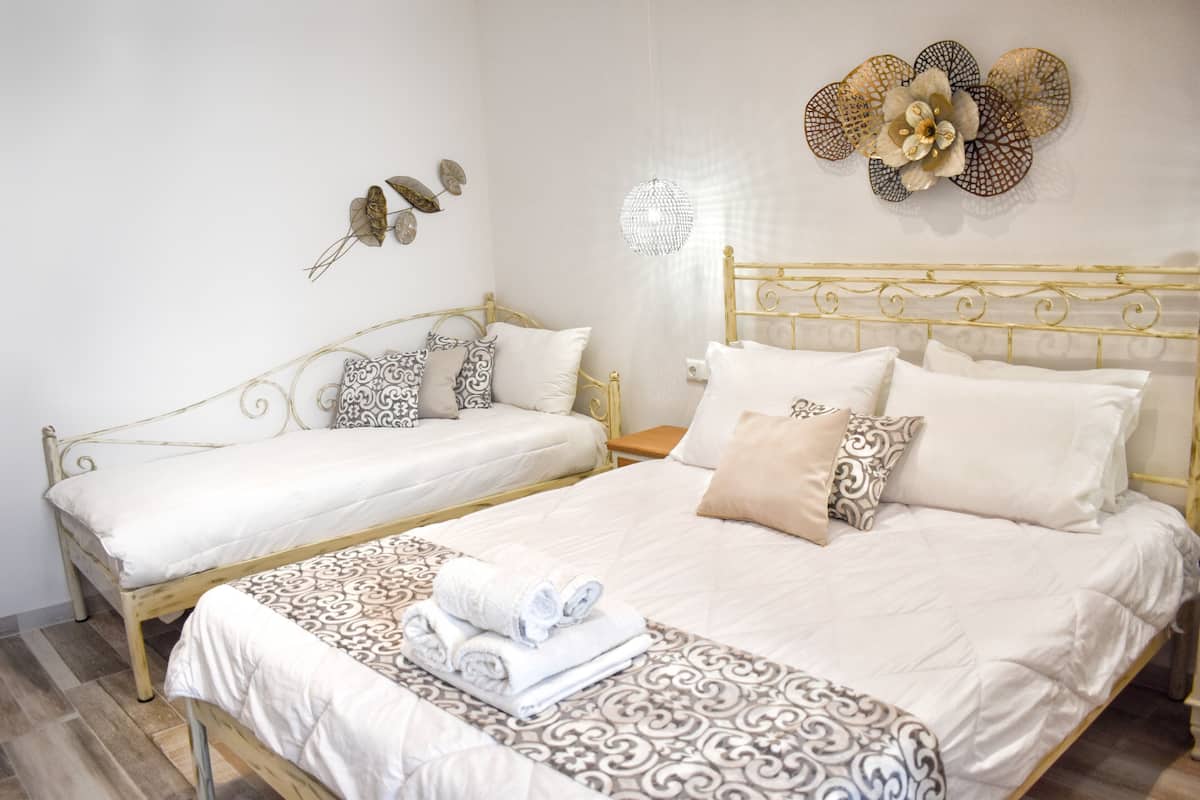 A hotel room with two beds, a decorative wall piece, and a chandelier.