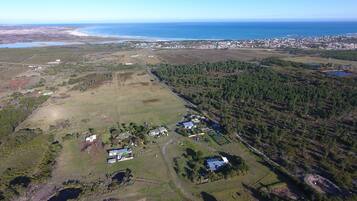 Vista aérea de una zona costera con edificios residenciales, campos abiertos y un bosque denso.