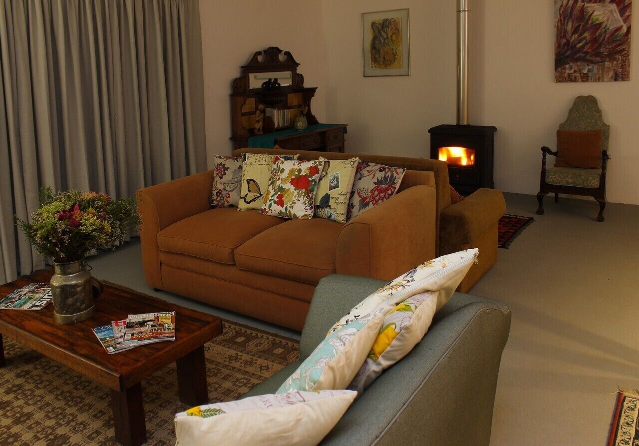 A cozy living room with a sofa, armchair, and a fireplace.