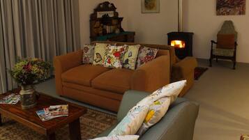 A cozy living room with a sofa, armchair, and a fireplace.