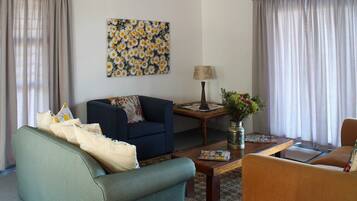 A living room with a blue sofa, a green armchair, a wooden coffee table, and a lamp.