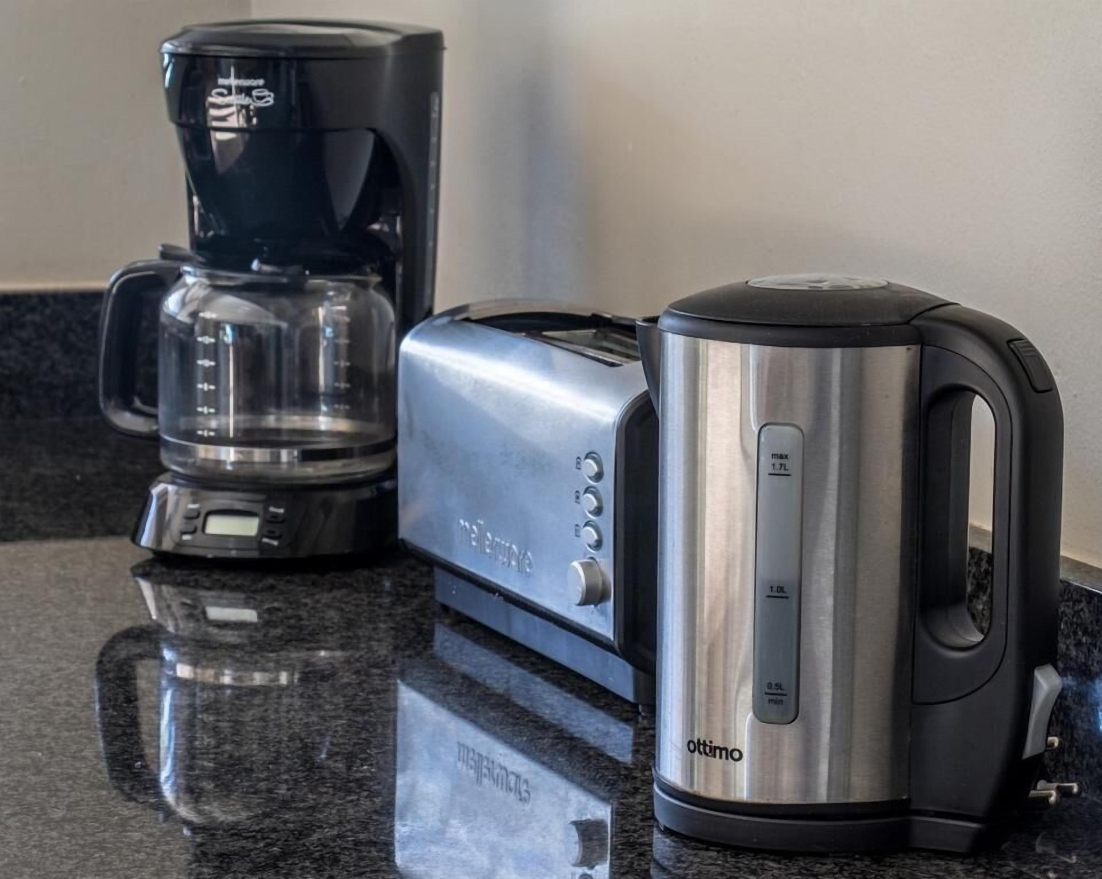 A kitchen counter with a coffee maker, a toaster, and a kettle.