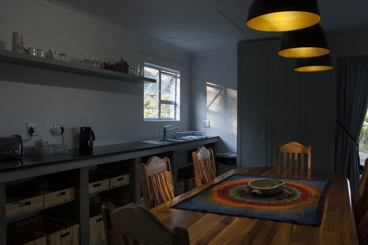 A modern kitchen with a wooden dining table, chairs, and pendant lights.