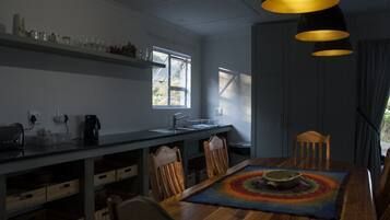 Une cuisine moderne avec une table à manger en bois, des chaises et des luminaires suspendus.