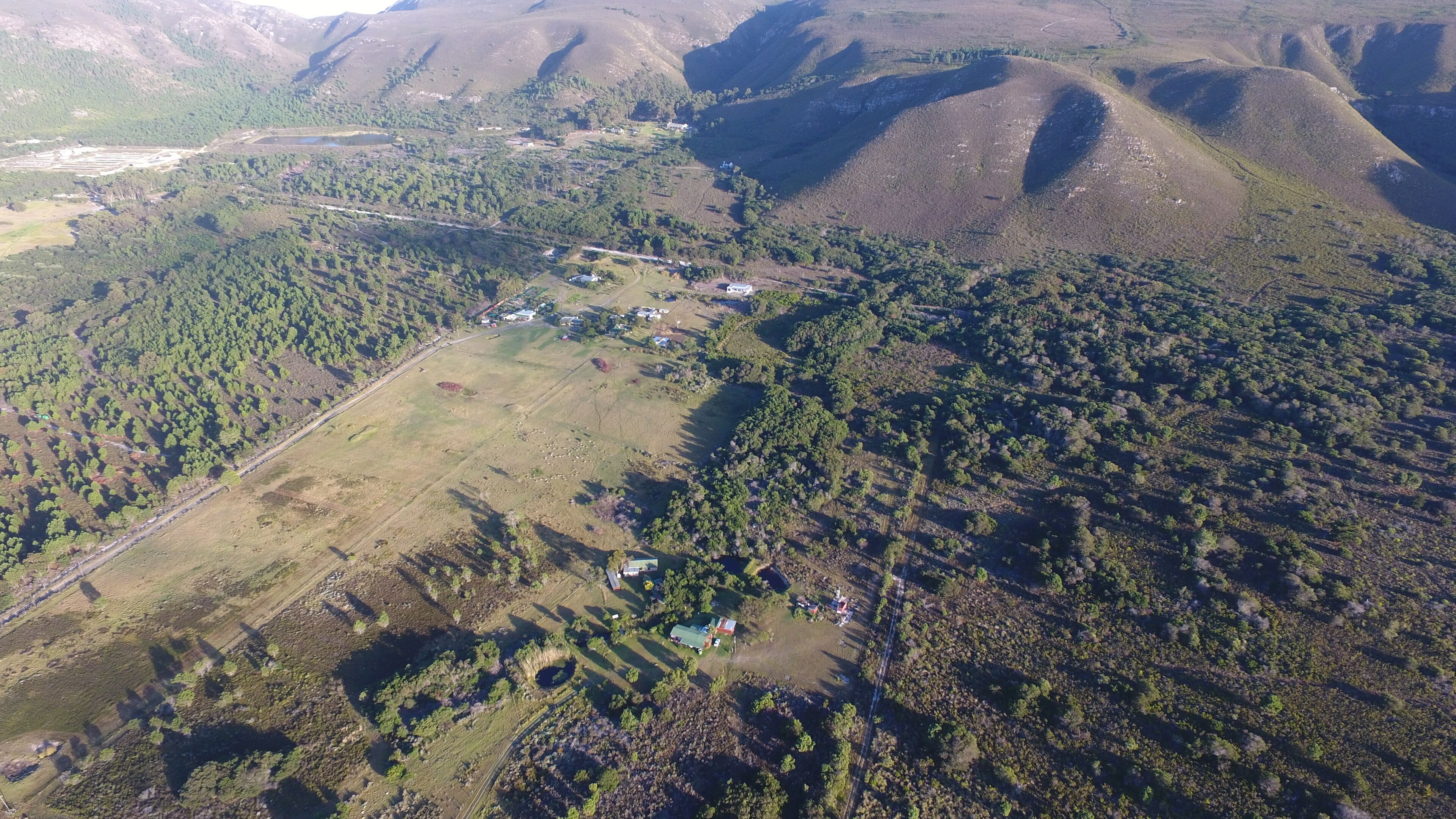 Vista aérea de una zona rural con casas dispersas, campos y bosques densos.