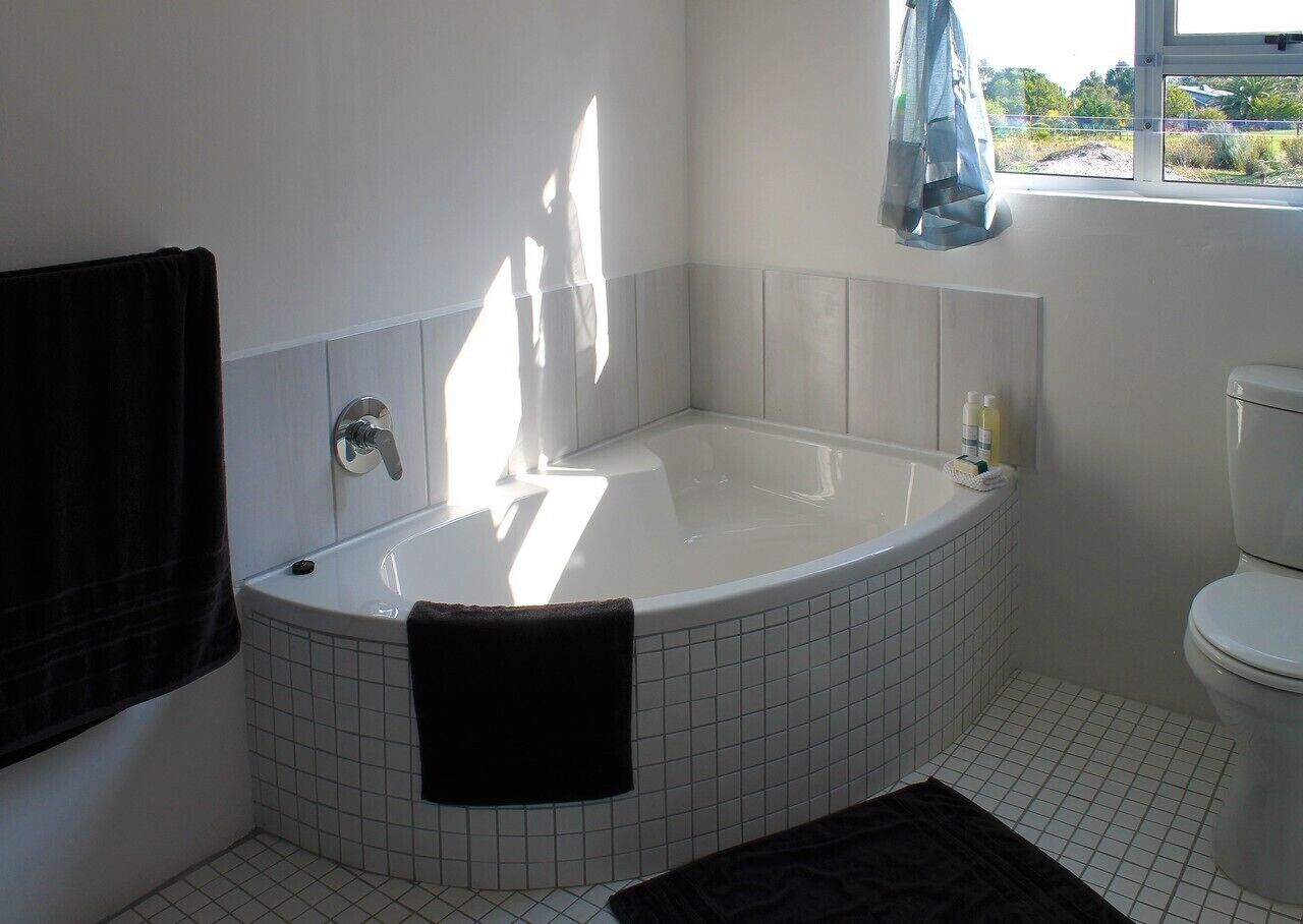 Une salle de bain avec une baignoire, des toilettes et une fenêtre.