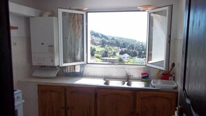 Una cocina con ventana, armarios de madera, un fregadero y un electrodoméstico blanco.