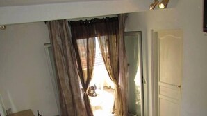 Un dormitorio con cama, escritorio, silla y ventana con cortinas.
