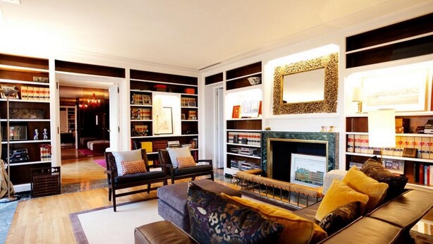 A spacious living room with a fireplace, leather sofas, and a large bookshelf filled with books and decorative items. - Magnificent high-rise penthouse in Barcelona (Barcelona)
