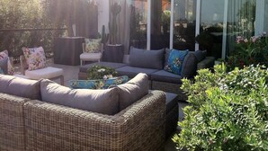 A sunlit outdoor seating area with wicker furniture, a small table, and potted plants. - Magnificent high-rise penthouse in Barcelona (Barcelona)