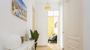 Un pasillo con una consola blanca, una planta en maceta y un cuadro en la pared.