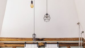Une pièce de style « loft » avec des poutres en bois apparentes, une table en bois rustique, un canapé et un téléviseur fixé au mur.